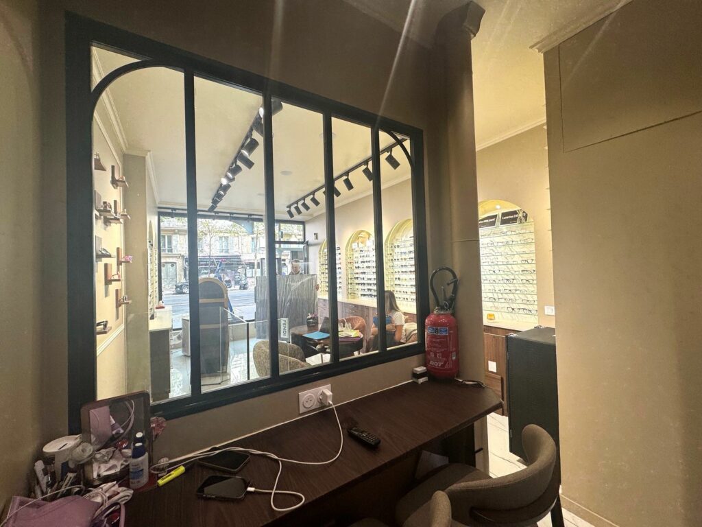 Boutique d’opticien après travaux à Paris 17e — Atelier avec verrière donnant sur la boutique